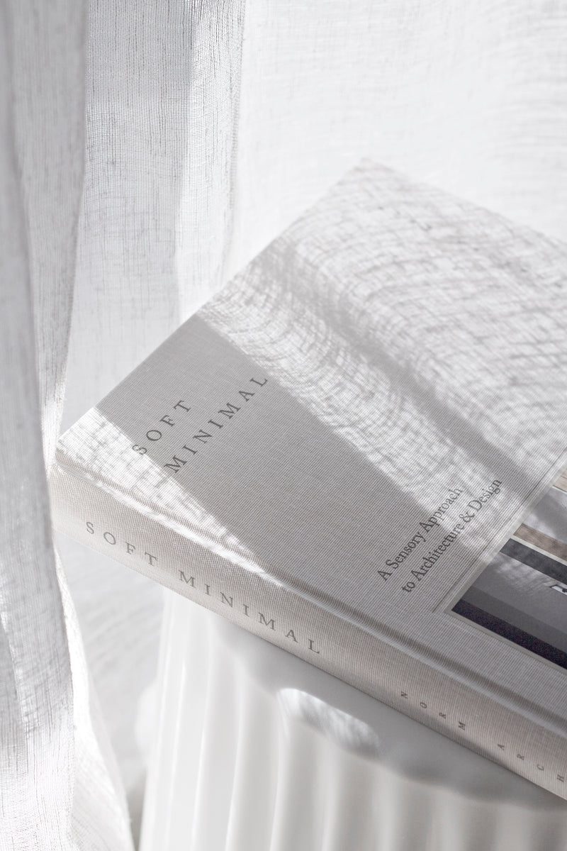 Soft Minimal book by Norm Architects styled on a white side table with natural light and linen curtains.