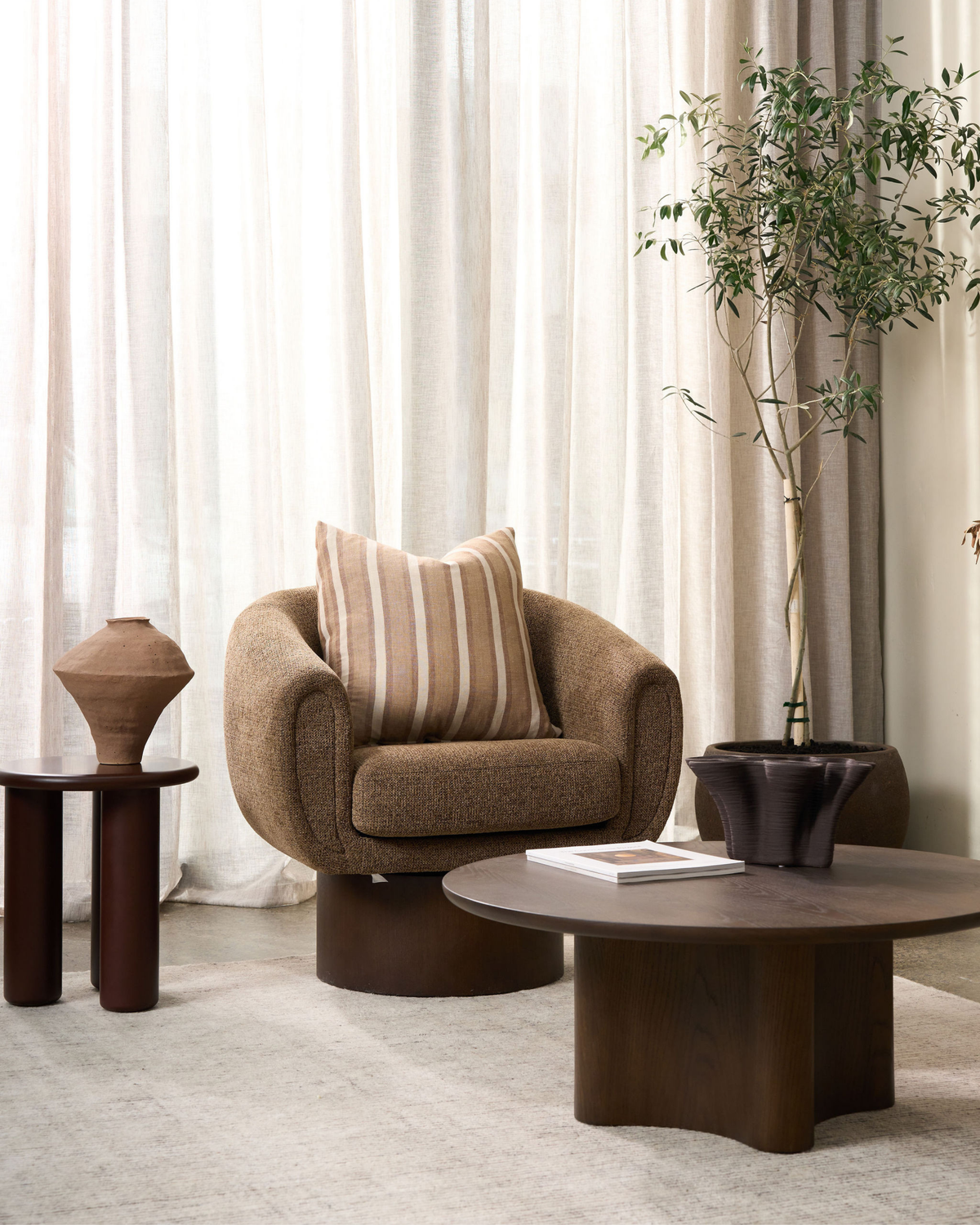 Living room with the Rouge side table beside a boucle armchair, olive tree and coffee table