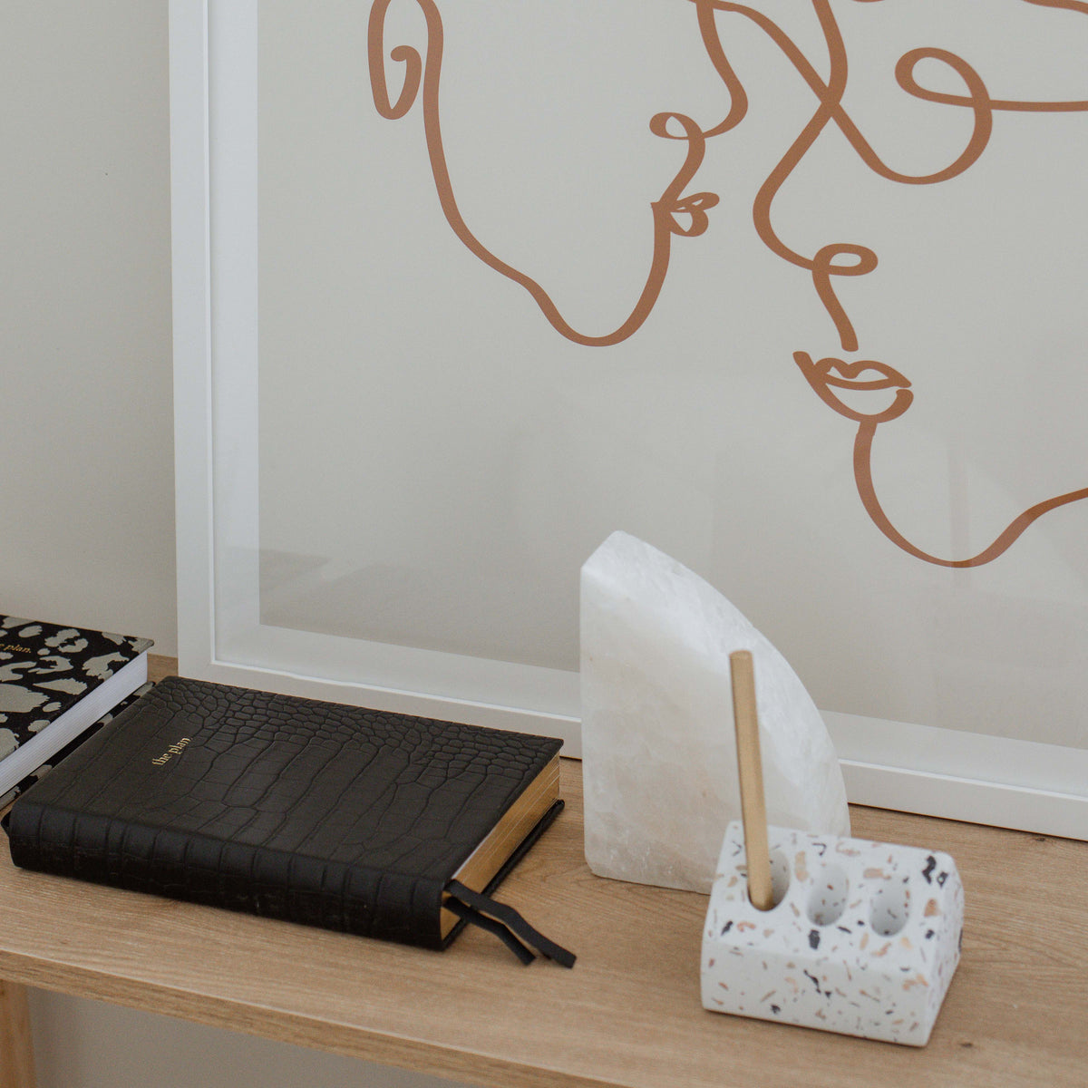 Marble rounded bookend on a desk with a line art print, notebook and pen holder