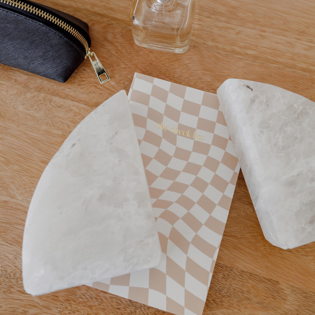 Pair of white marble rounded bookends lying on a desk beside a checked notebook