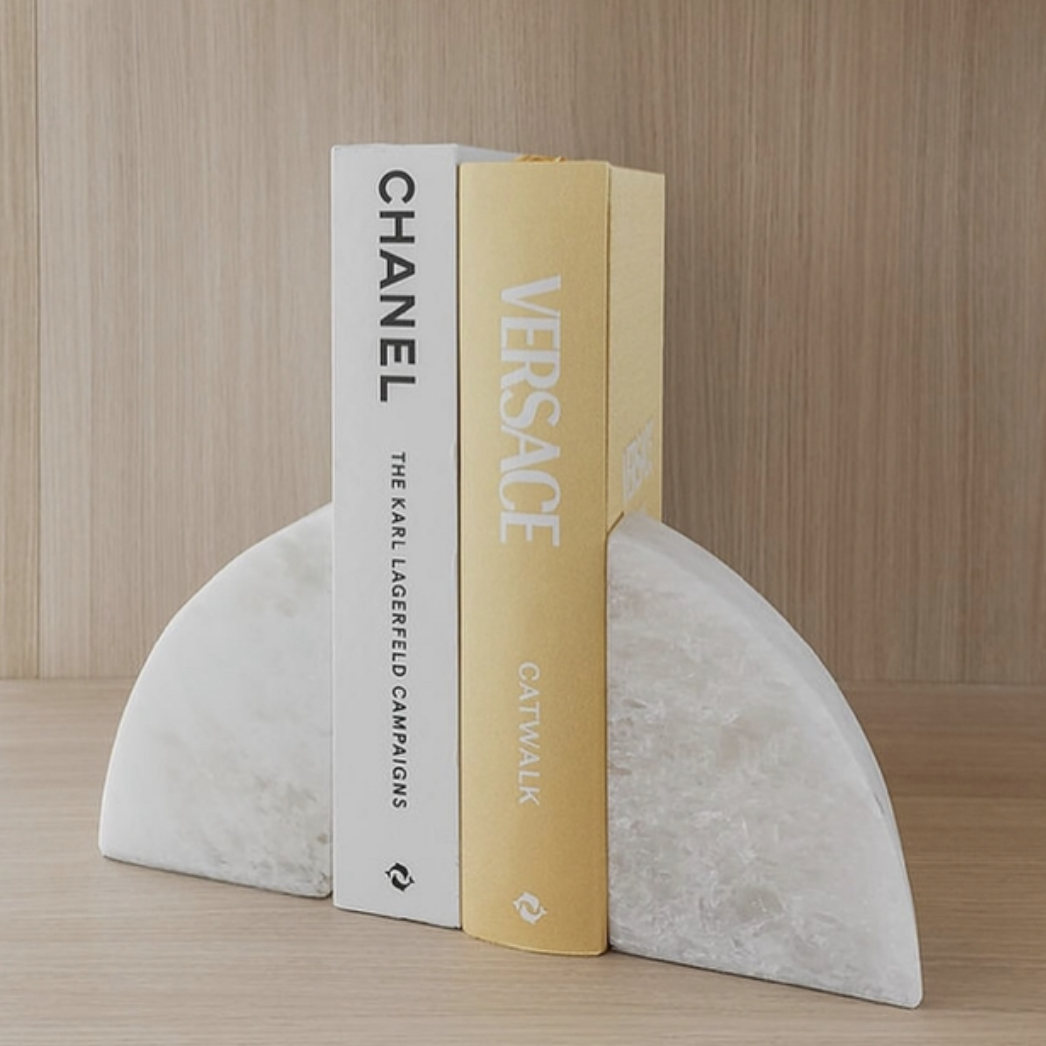 Solid marble rounded bookends holding two books on a timber shelf