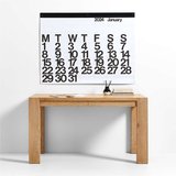 2024 Stendig Calendar by Massimo Vignelli hanging above an oak console table styled with books and a diffuser