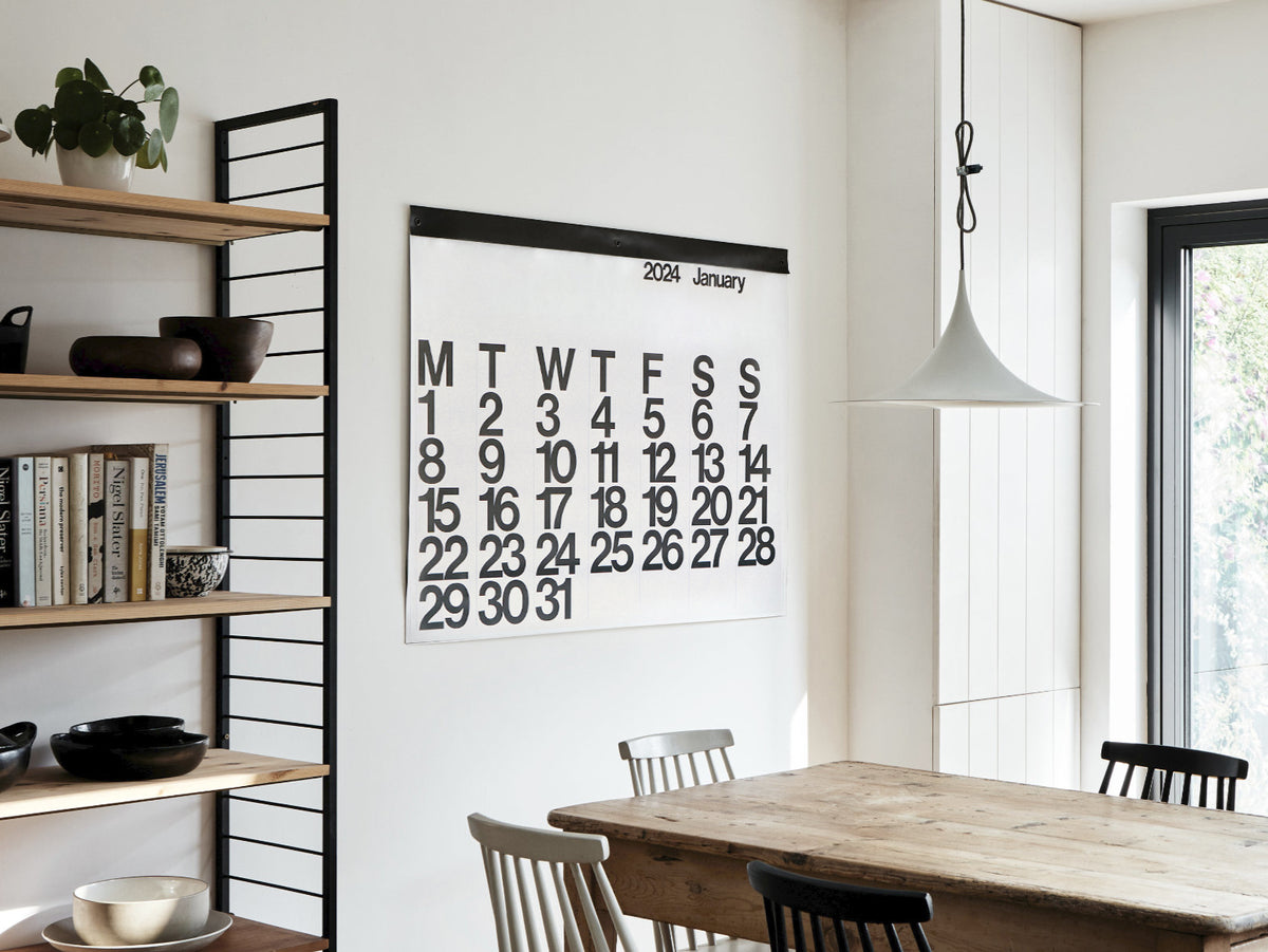 Oversized Stendig wall calendar hanging in a modern dining and kitchen space
