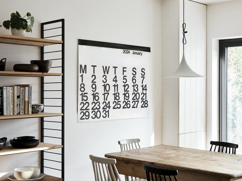 Stendig wall calendar styled in dining room with vintage wooden table and chairs