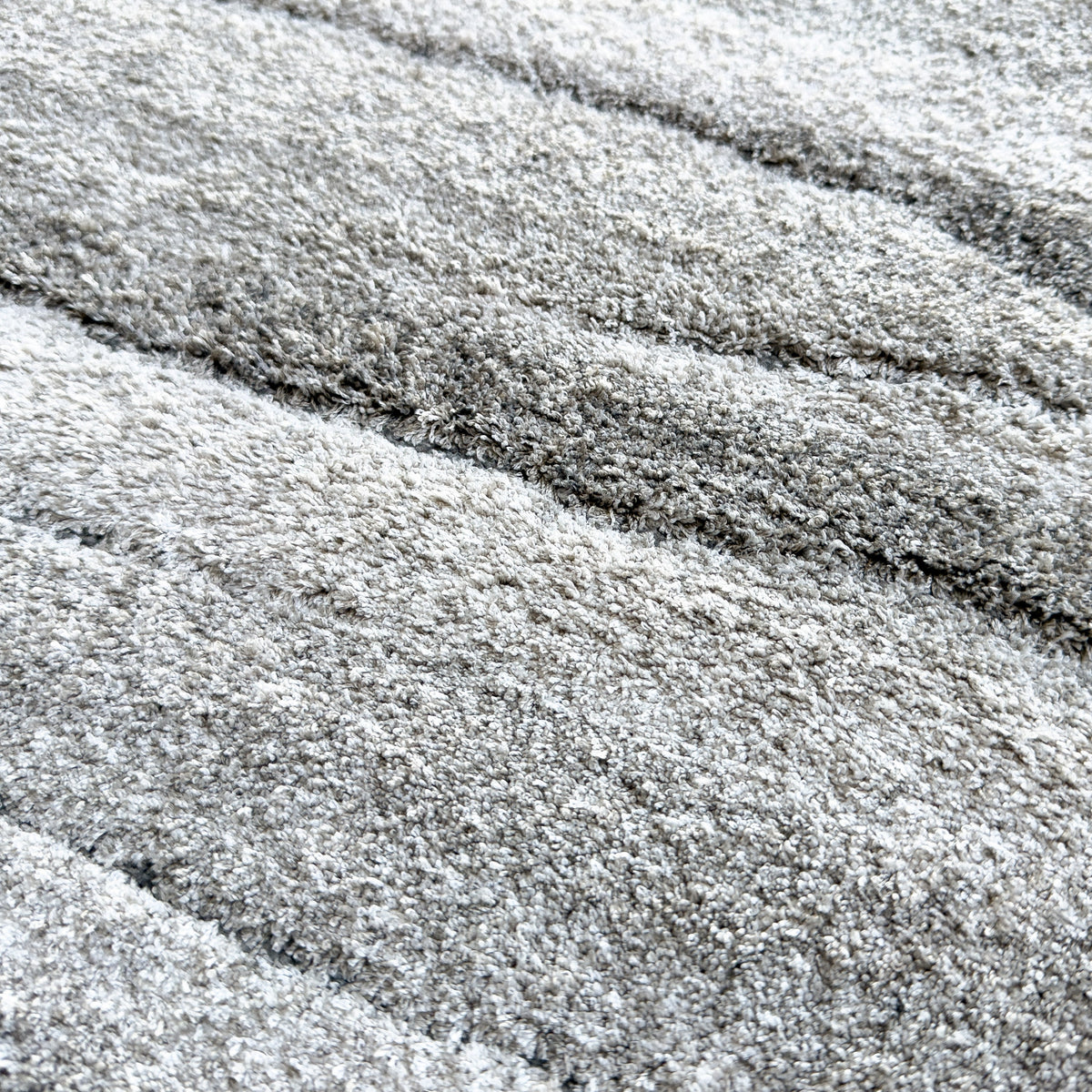 Close view of the plush drift grey pile and its layered tones