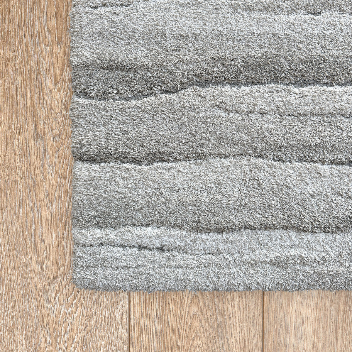 Corner of the drift grey rug on a timber floor