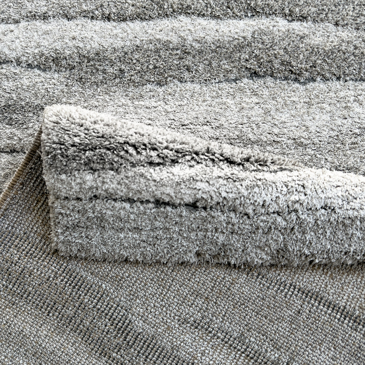 Folded edge of the drift grey rug showing the plush pile and backing
