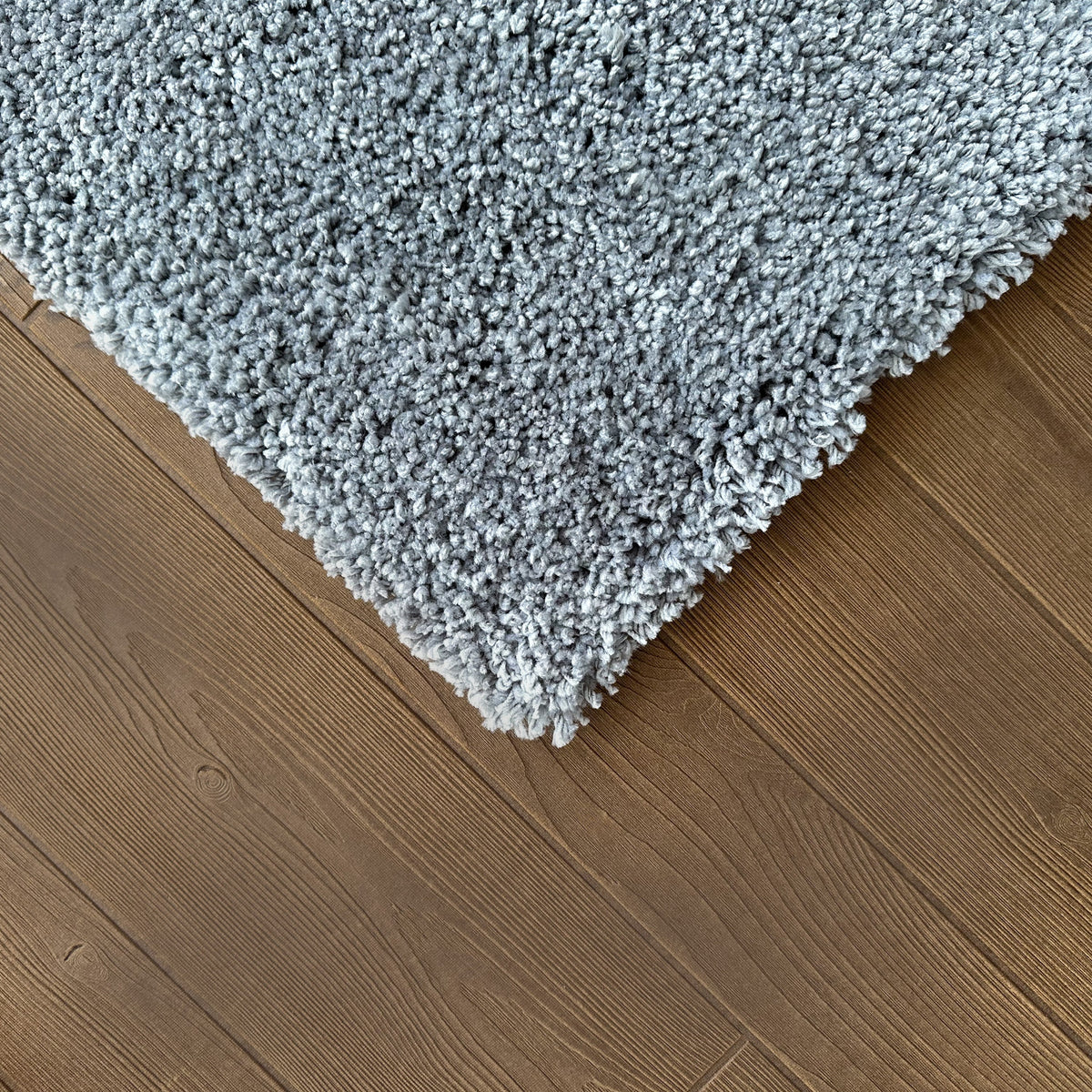Corner of the ash grey rug on a dark timber floor