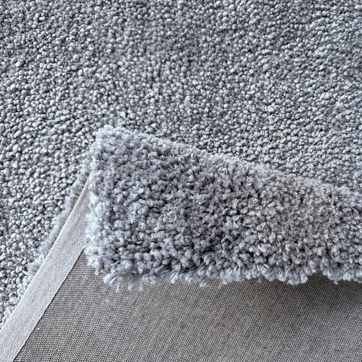 Folded edge of the ash grey rug showing the pile depth and backing