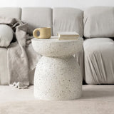 A Pedestal Side Table - Fleck White by Flux Home sitting on a couch next to a cup of coffee.