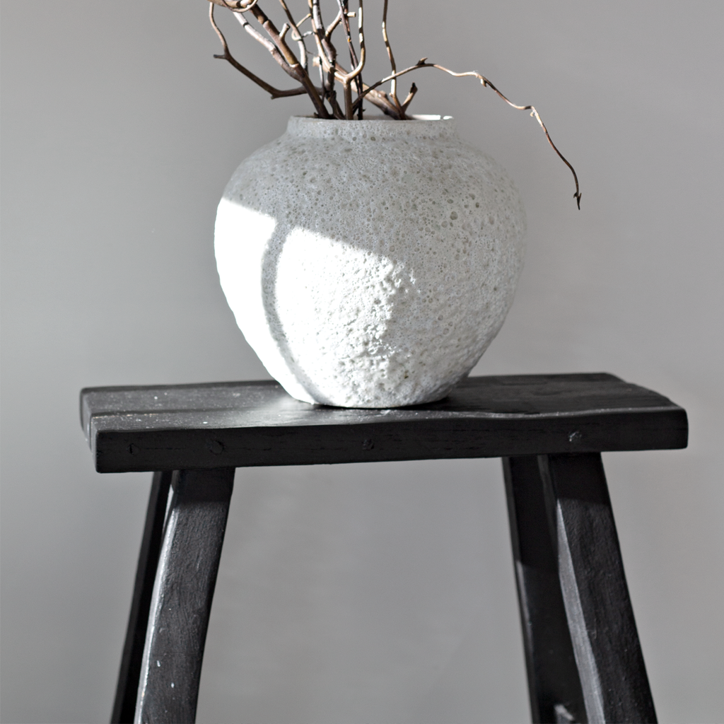 Short Seafoam vase of branches on a black timber stool against a grey wall