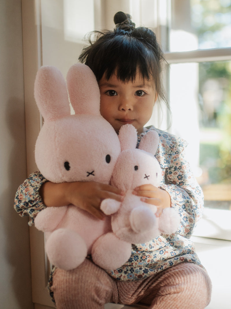 A 100% Miffy Sitting Terry Pink (33cm) plush CE certified little girl holding two pink bunny stuffed animals by Mr Maria.