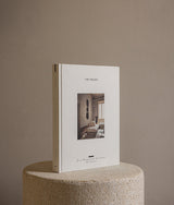 Hardcover design book The Touch: Spaces Designed for the Senses displayed on a textured stone pedestal, minimalist neutral background.