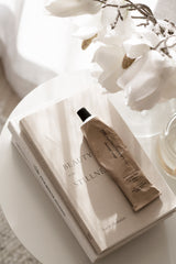 Therapy hand cream Soothe Peony & Petitgrain styled on neutral coffee table with book and flowers