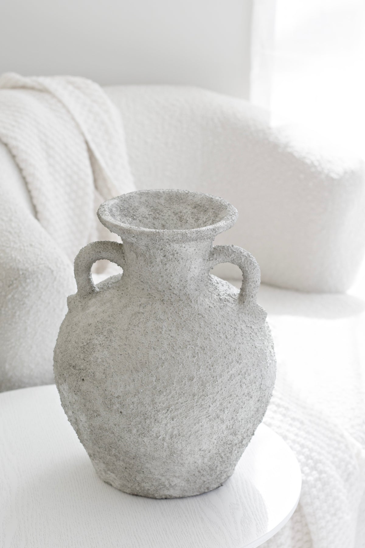Thira Vase styled beside a white armchair in a neutral-toned setting