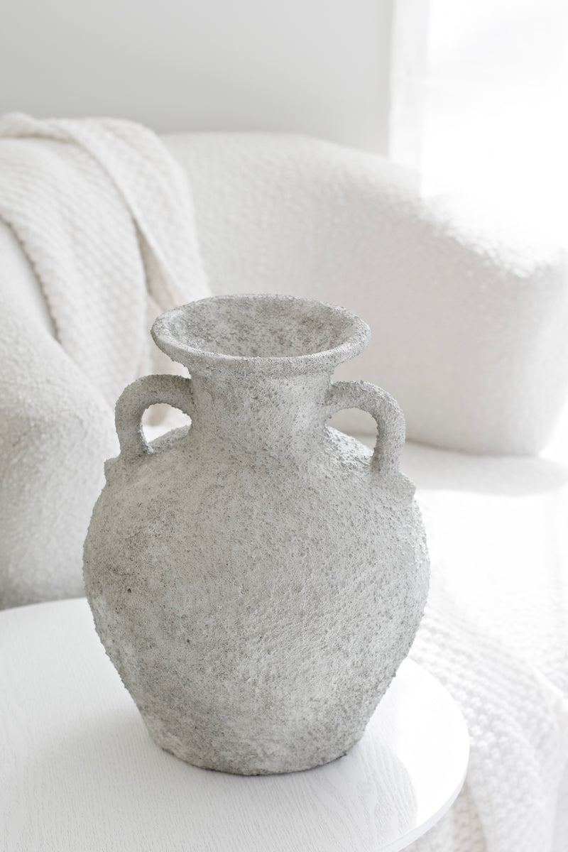 Thira Vase styled beside a white armchair in a neutral-toned setting