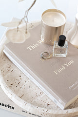 This Was Meant to Find You book styled with gold candle and perfume on a stone tray in a neutral setting