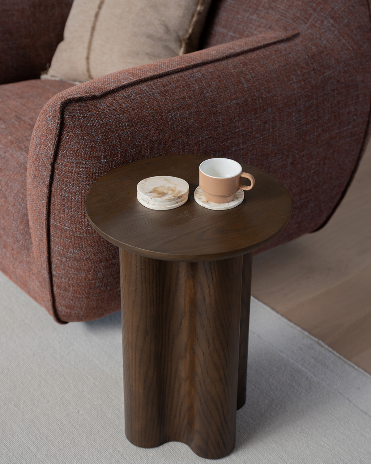 Tiramisu coasters on a dark timber side table by a rust armchair, one holding a tan mug