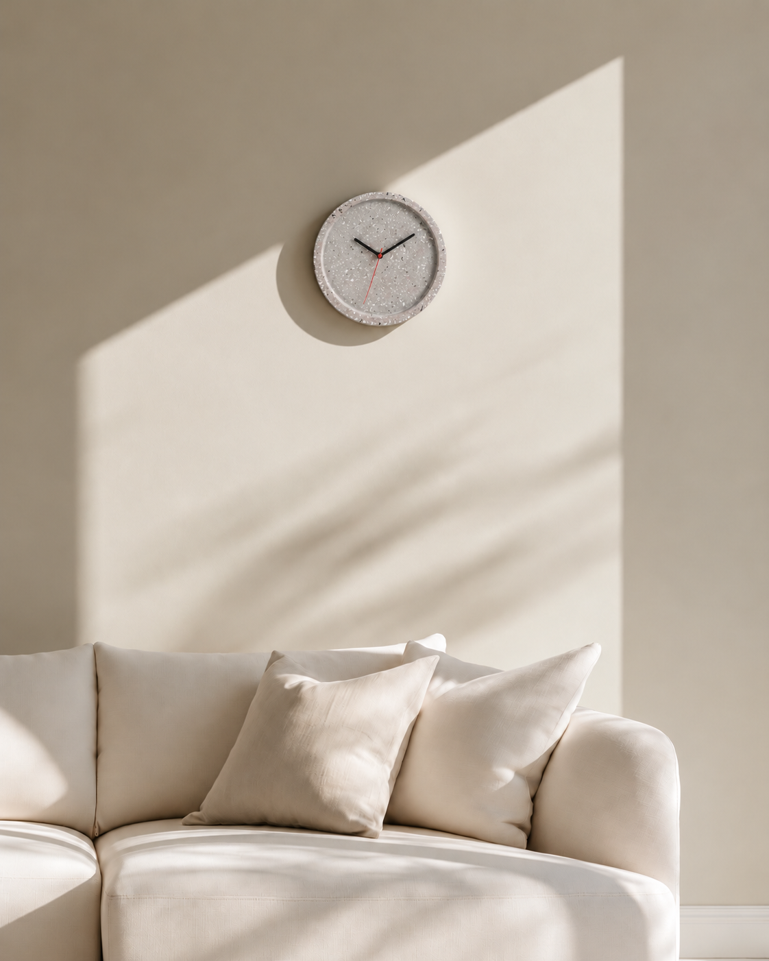 Tom Terrazzo Wall Clock 26cm by Karlsson above a cream sofa in warm afternoon sun
