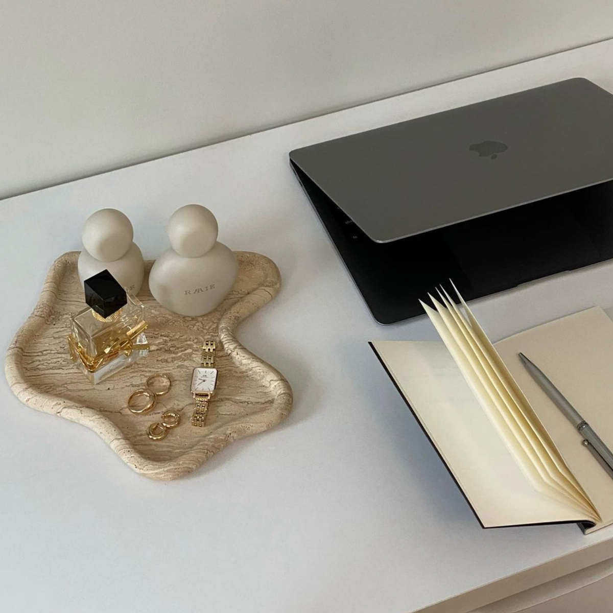 Travertine curved tray with jewellery on a desk beside a laptop and notebook