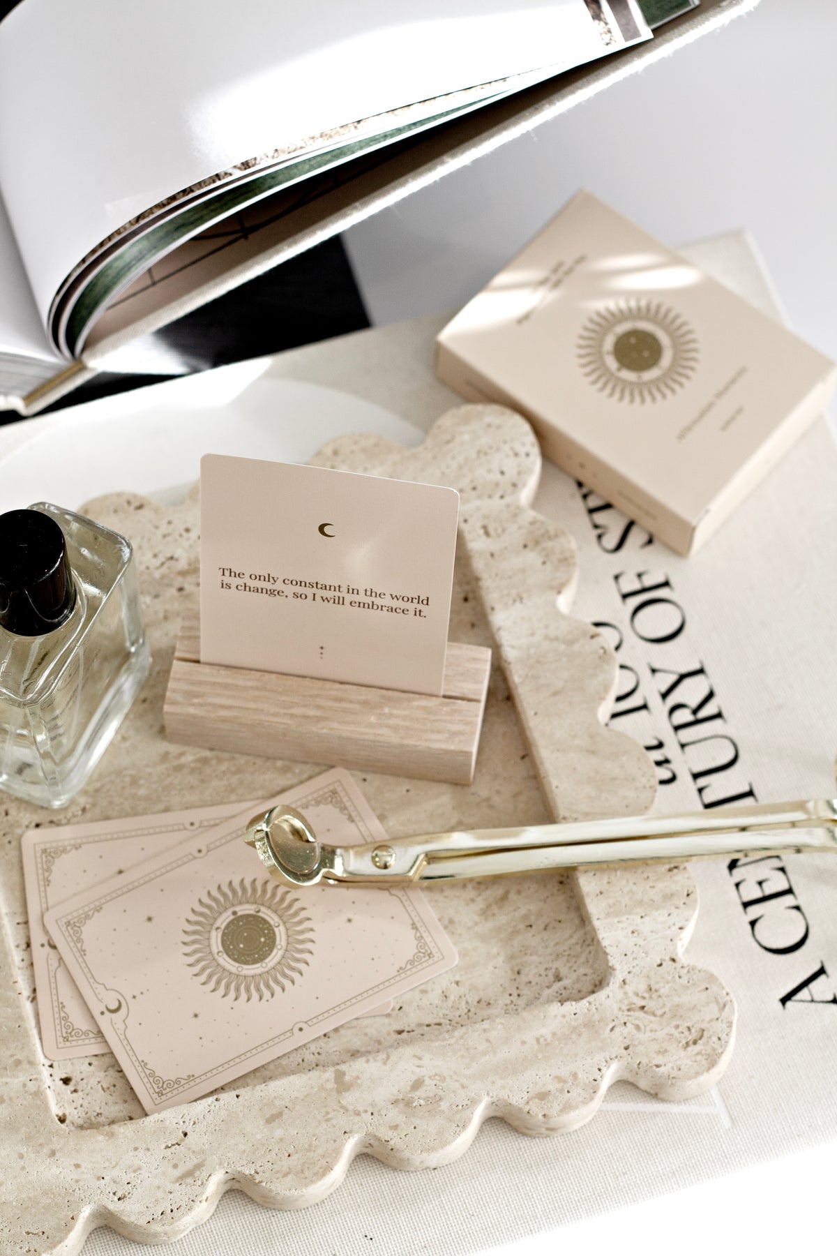 Close-up of travertine scalloped tray styled with cards, perfume, and accessories on a coffee table, showcasing natural stone texture and wavy edges.