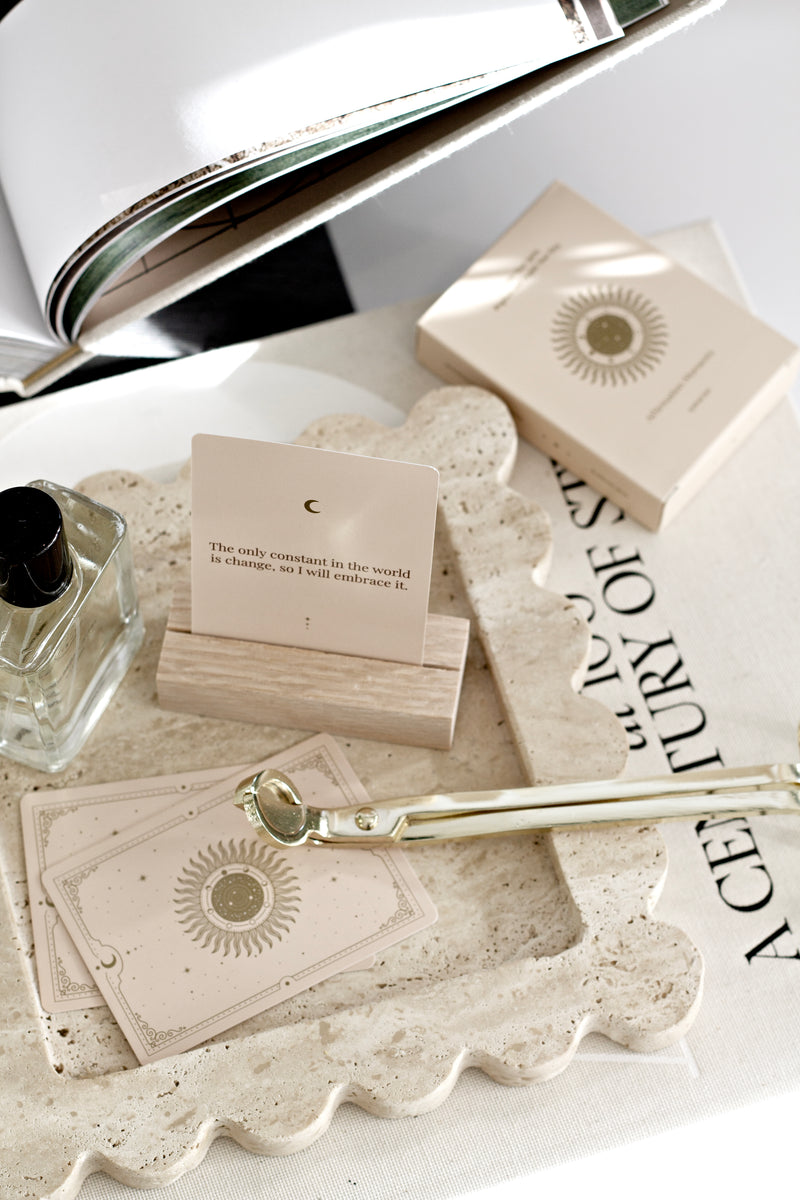 Close-up of travertine scalloped tray styled with cards, perfume, and accessories on a coffee table, showcasing natural stone texture and wavy edges.