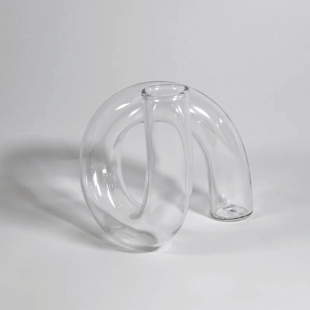Clear J-Curve vase front on, casting a soft shadow across a pale grey surface
