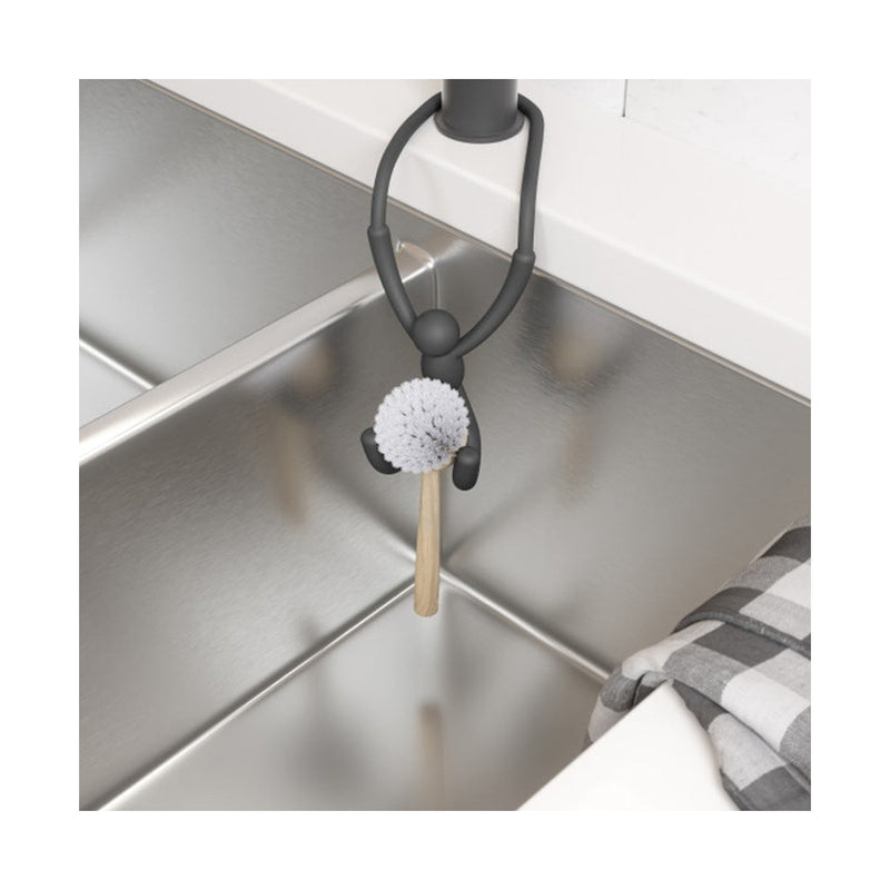 A Umbra Buddy Flex Sink Caddy - Black, made by Umbra, is a kitchen organised stainless steel sink with a brush attached to it, made of flexible materials.