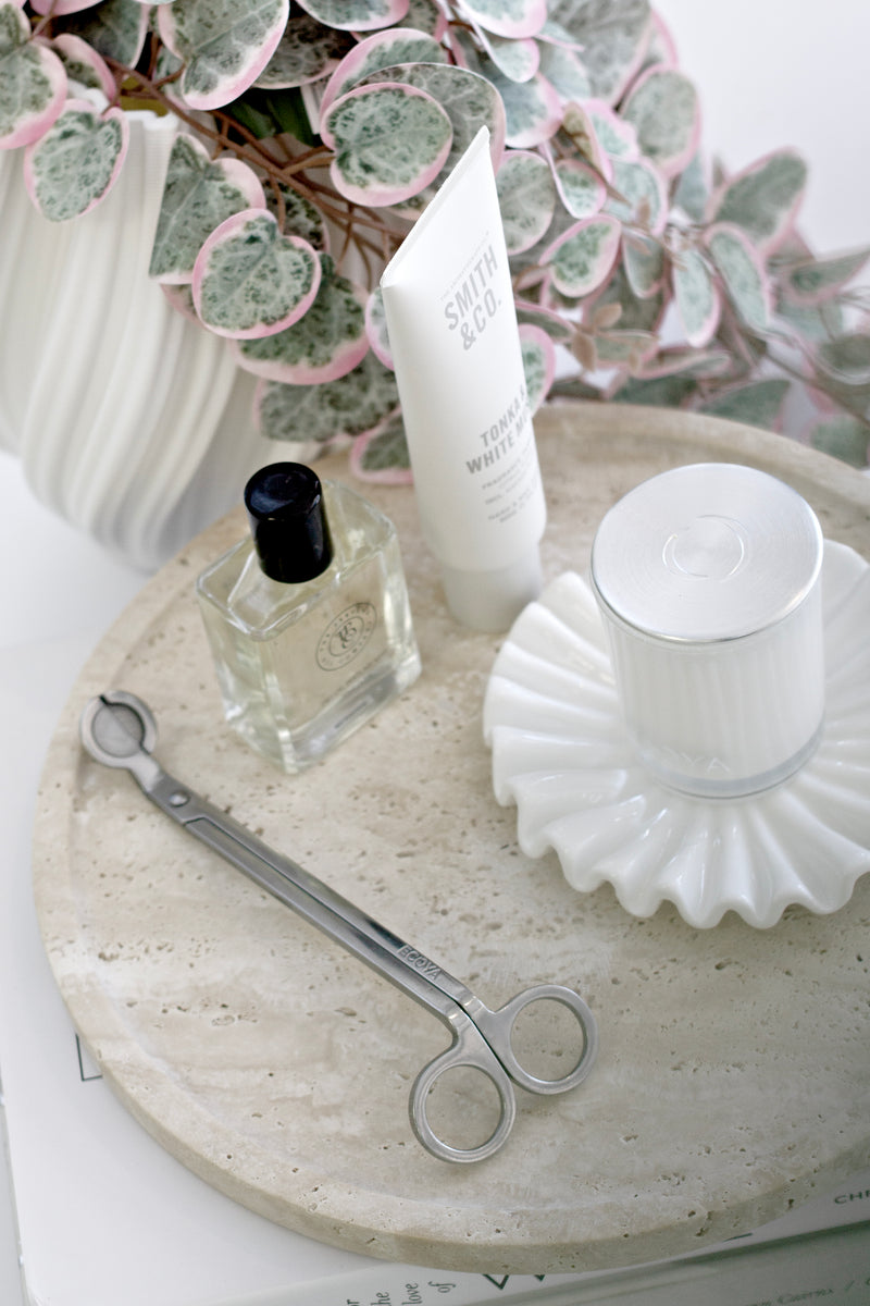 Variegated pink and green string of hearts faux vine styled behind a round stone tray with bathroom essentials