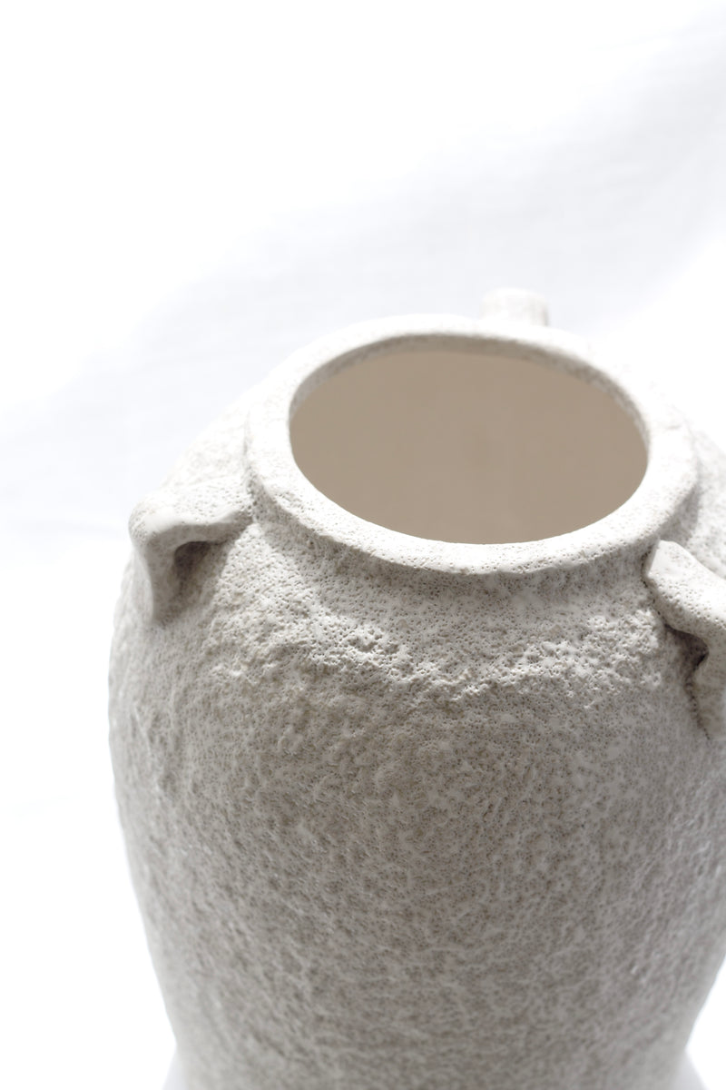 Close-up of the top of the sculptural beige vase showing raw textured finish and interior glaze