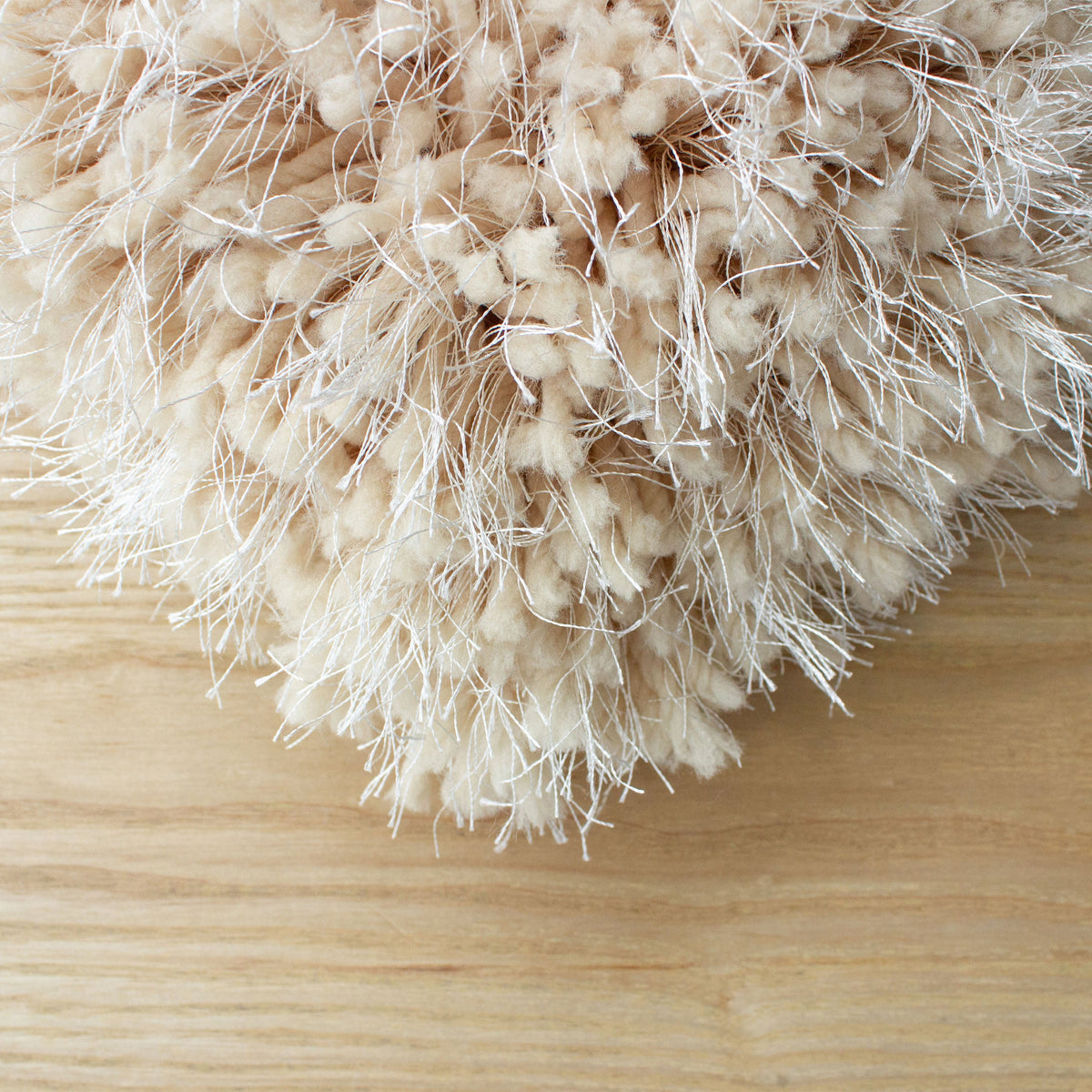 Rounded corner of the beige shag rug on a light timber floor