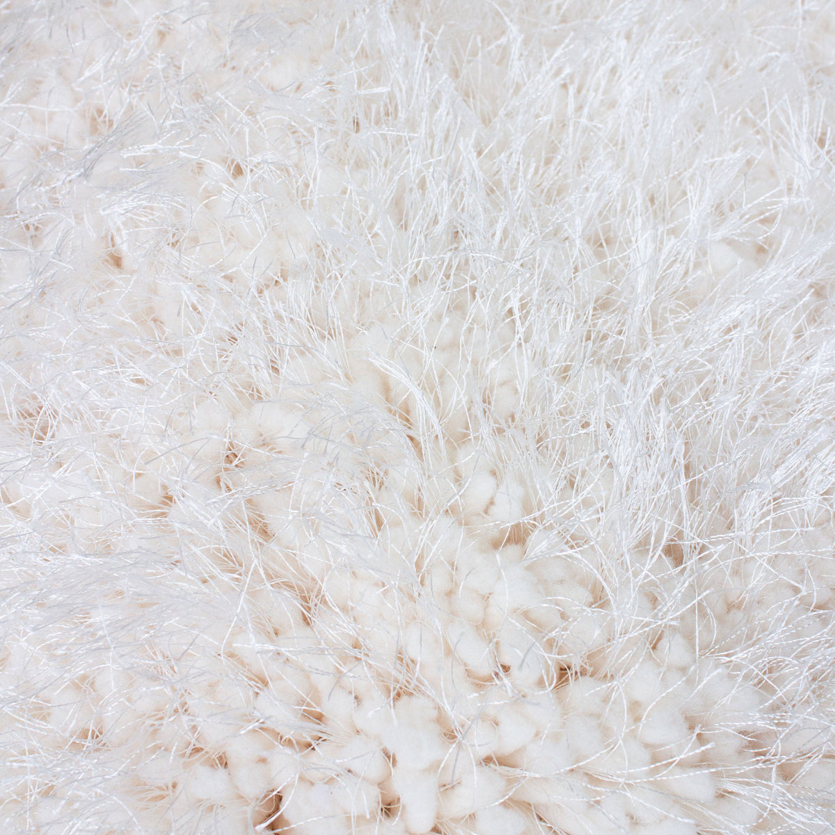 Edge of the white shag rug folded back to show its grey backing
