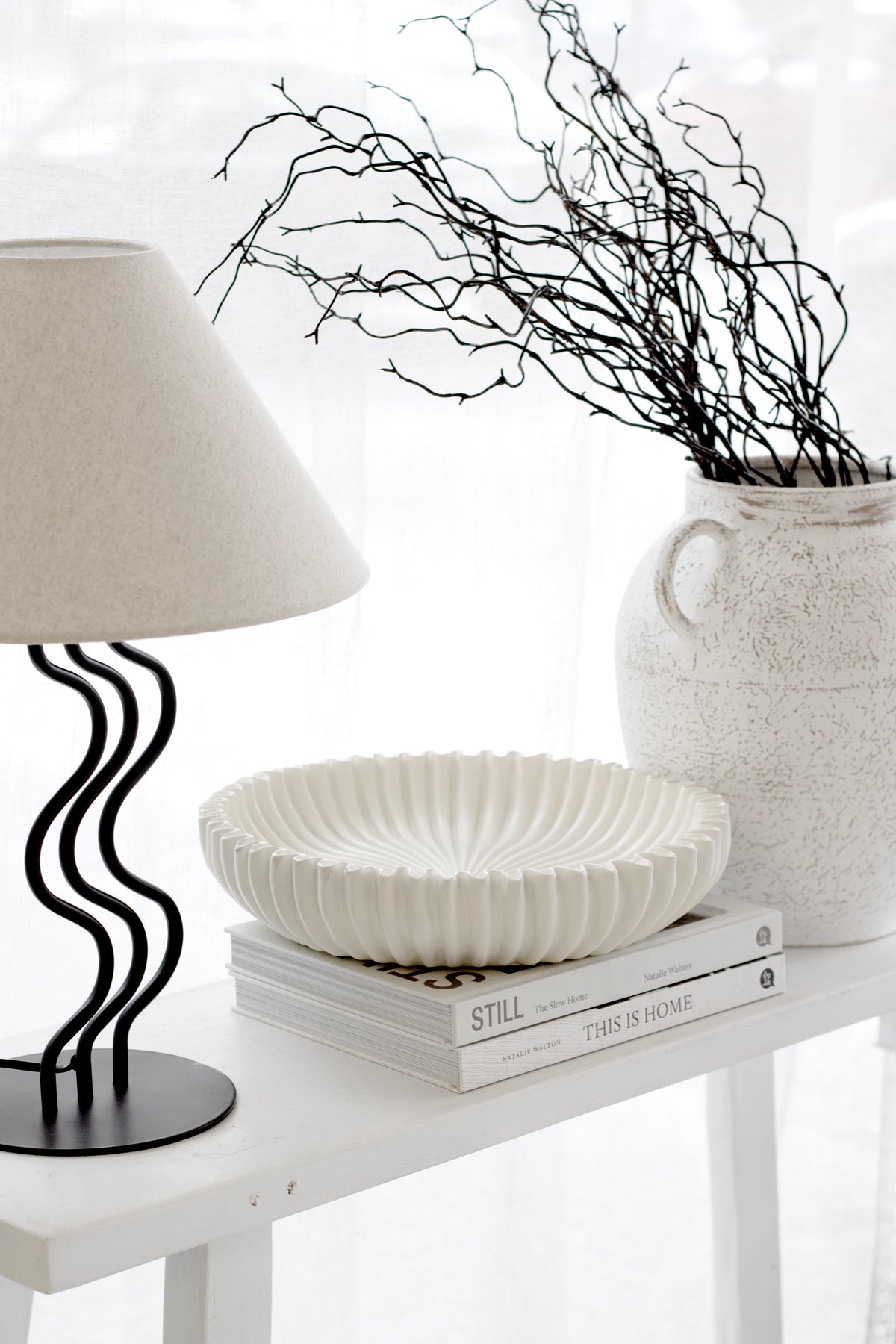 Neutral console styling with the sculptural Vince Vase in ceramic, paired with books and a modern lamp.
