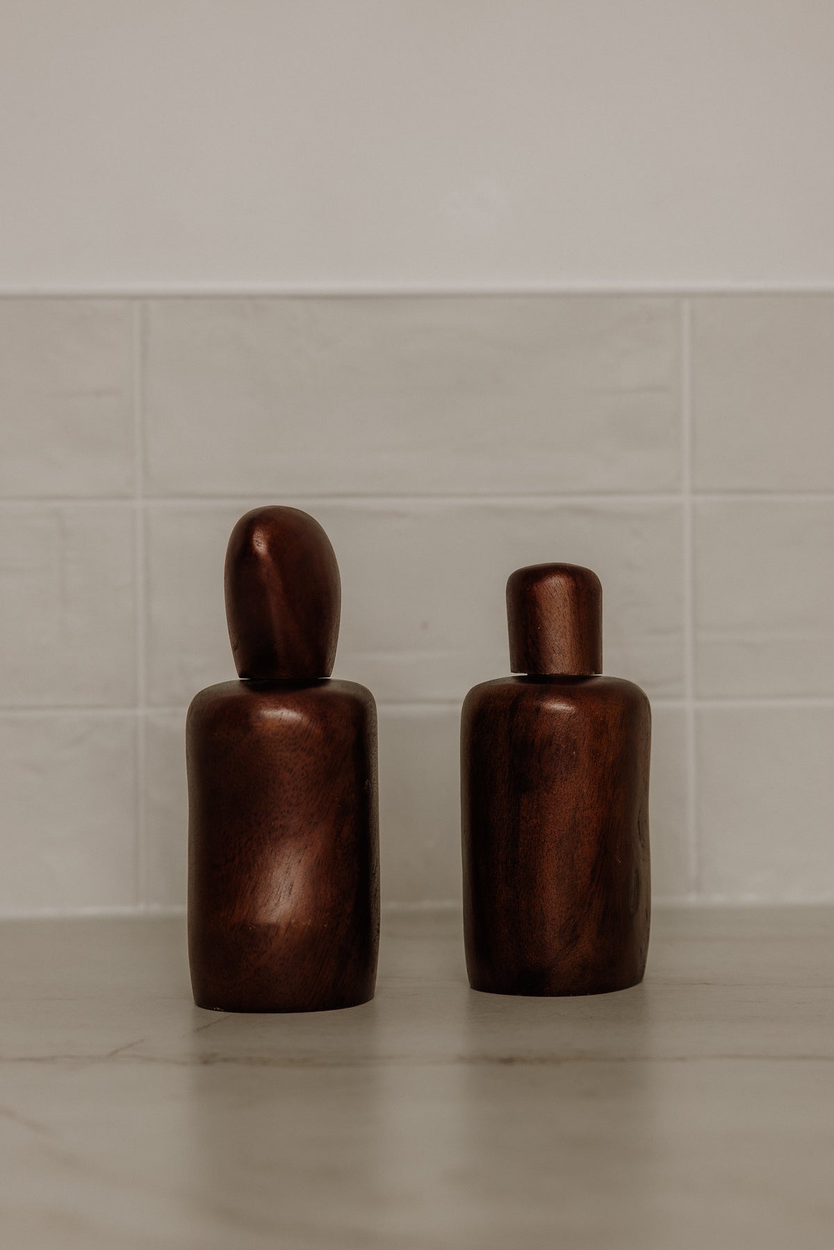 Dark brown wavy salt and pepper shakers on a pale stone bench