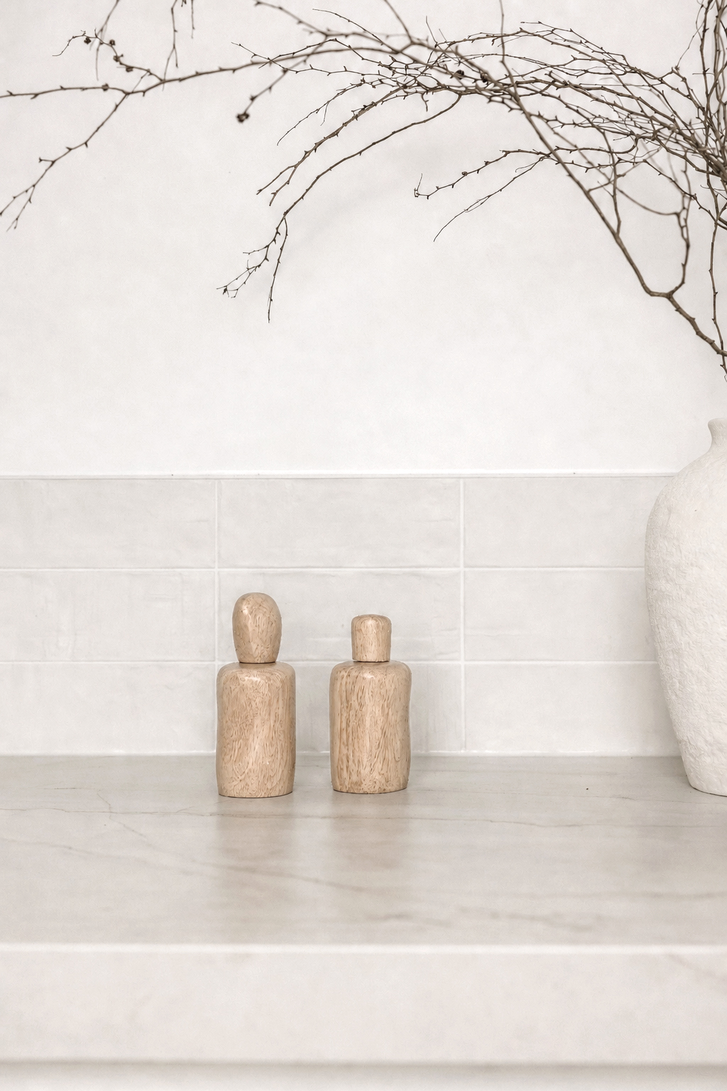 Natural wavy salt and pepper shakers on a stone shelf with dried branches
