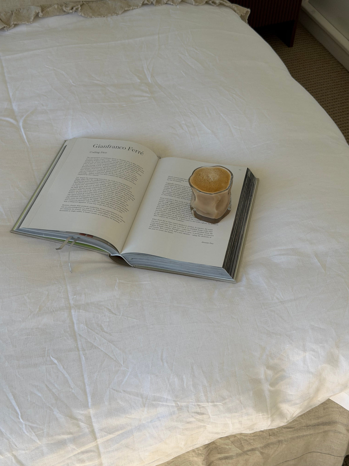Wavy textured glass resting on an open book on a white bed