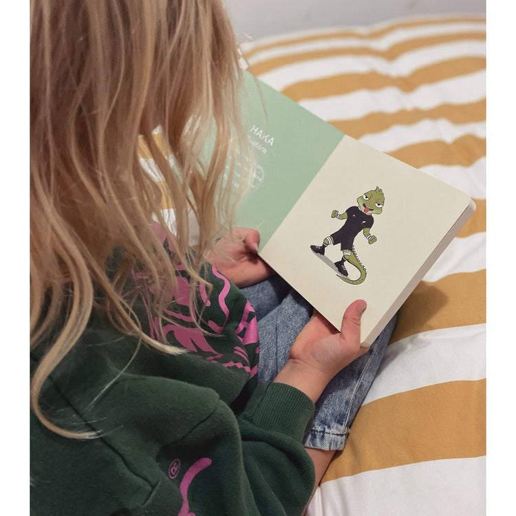 Child reading Wild About Footy on a striped cushion