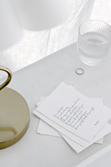 Minimal empowerment quote print cards styled on white bedside table with glass tumbler and brass lamp base