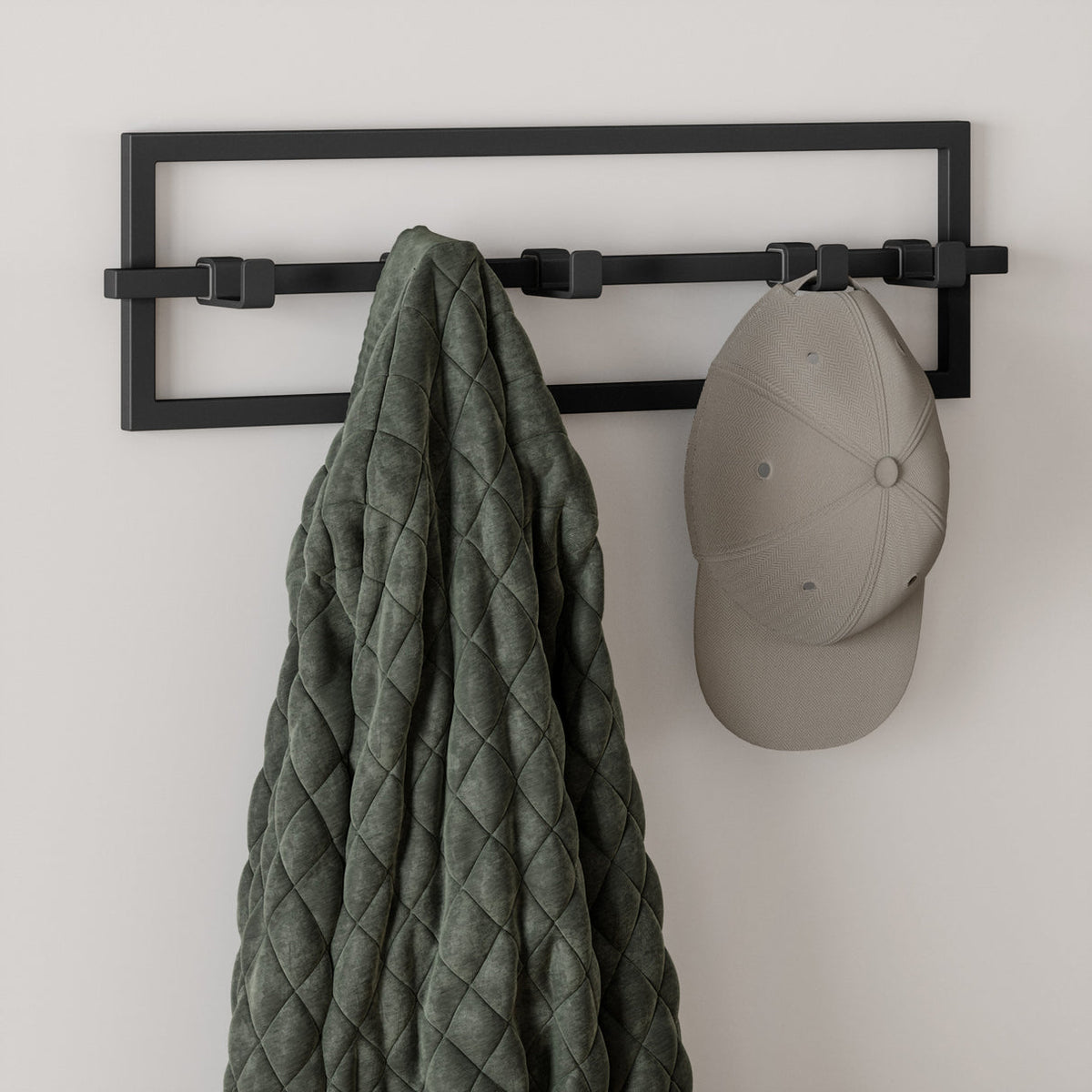 Umbra Cubiko 5 hook wall rack in black holding a quilted olive coat and a cap