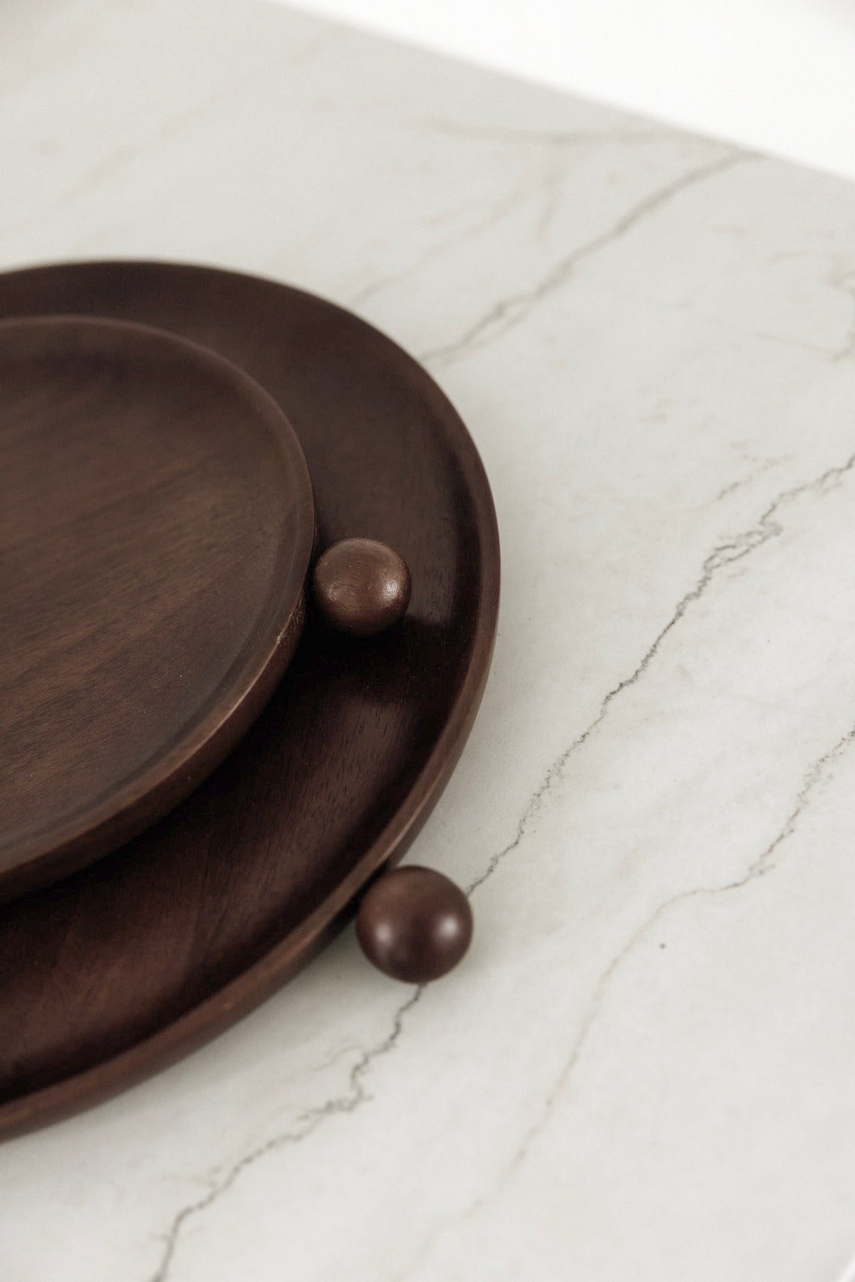 Close-up of the dark brown mango wood tray edge on a marble benchtop