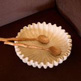 Wooden salad servers styled in a ceramic bowl on a dining table