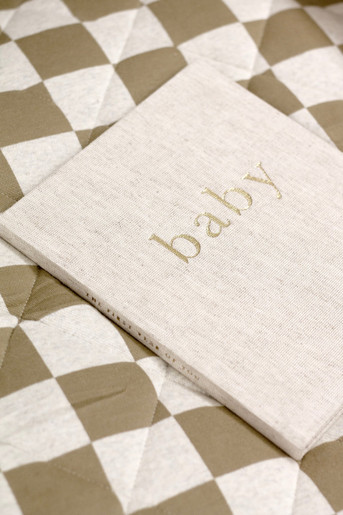 Write To Me First Year of You baby journal in oatmeal linen on a checked quilt