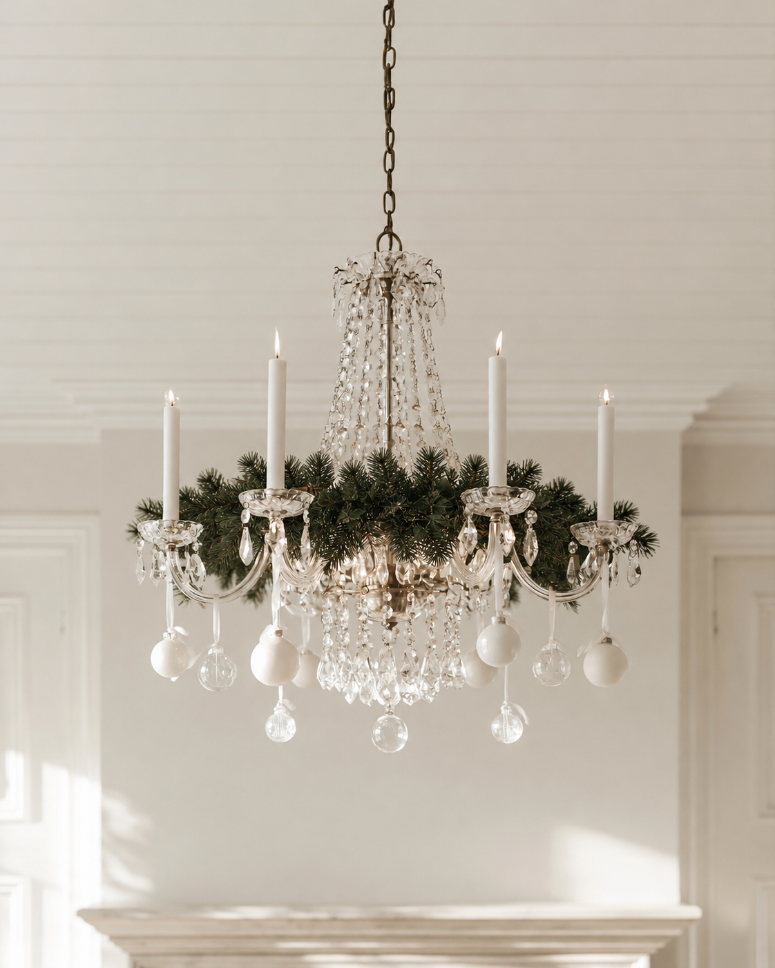 Royale Christmas Garland wound around a crystal chandelier with white candles and baubles