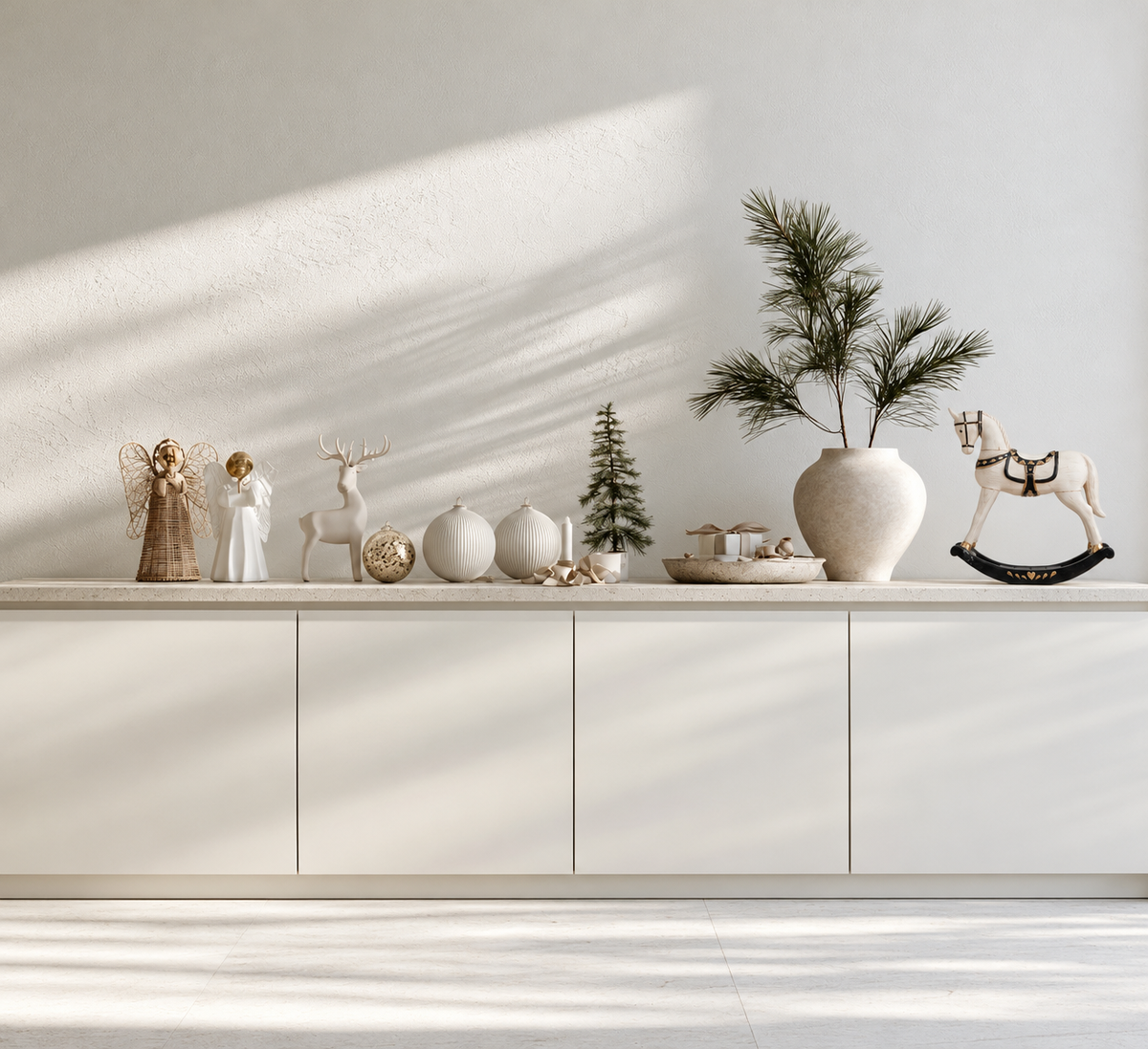White rocking horse ornament with black rockers on a white sideboard beside a stoneware vase of pine