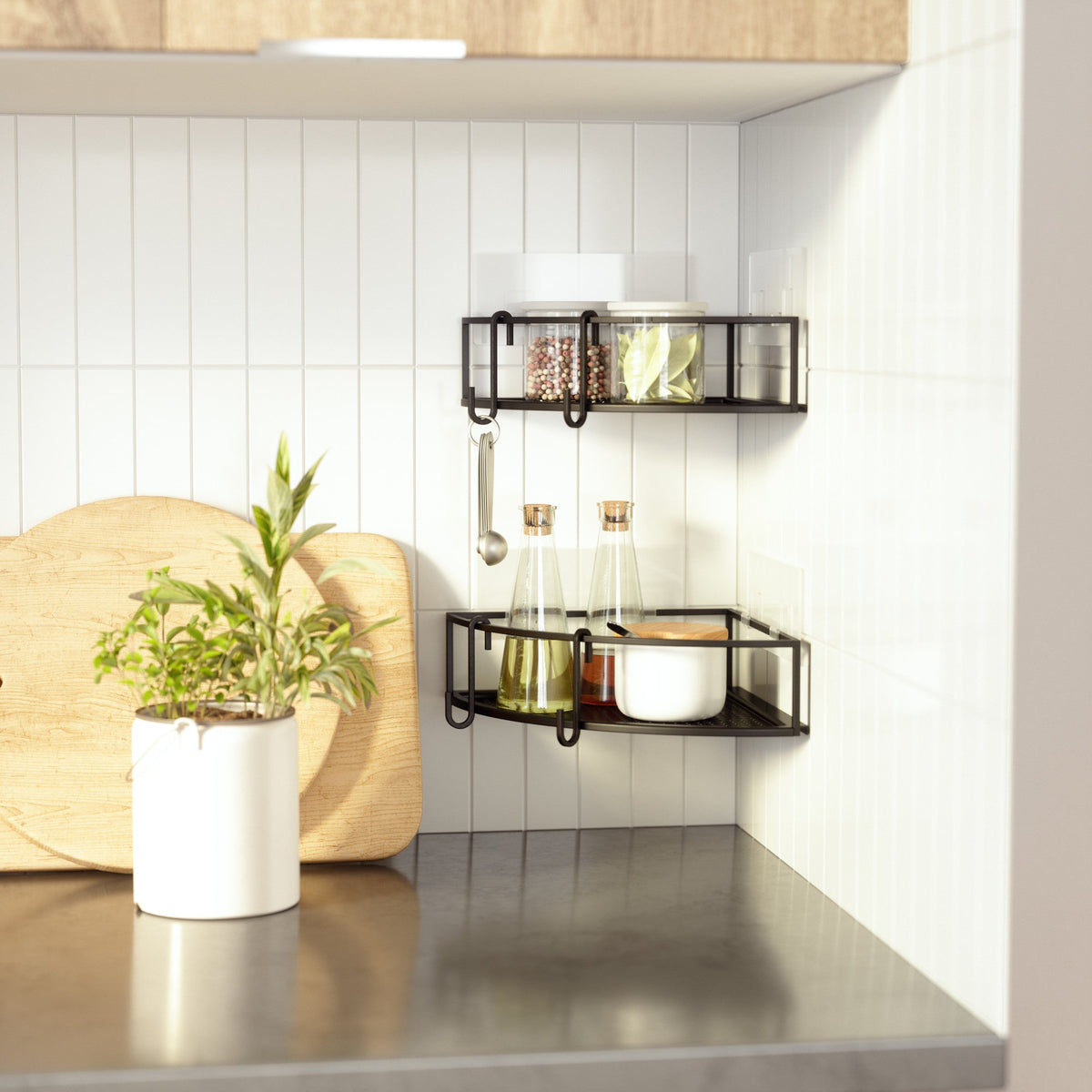 Black Cubiko corner bins on a tiled kitchen wall above a potted plant