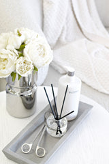 Zakkia Natural Rectangle Tray styled with diffuser, lotion bottle, and silver vase of white flowers – minimal modern look