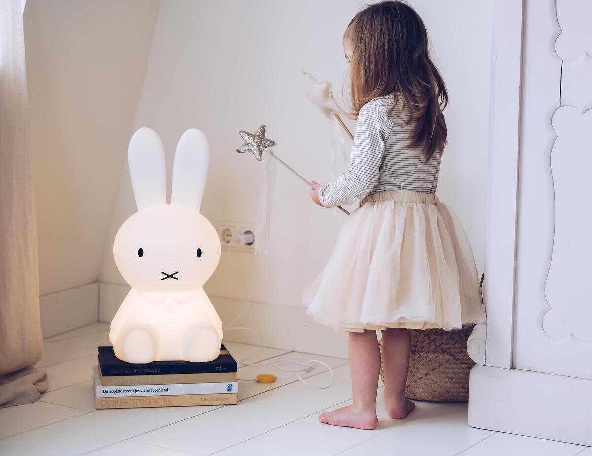 A young girl standing beside the Mr Maria Miffy Star Light bunny lamp