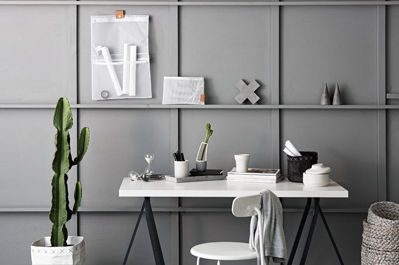 A white desk and cactus in a room with grey walls. The desk is adorned with a Zakkia Concrete Cross Trivet - Natural, adding a touch of natural beauty to the space.