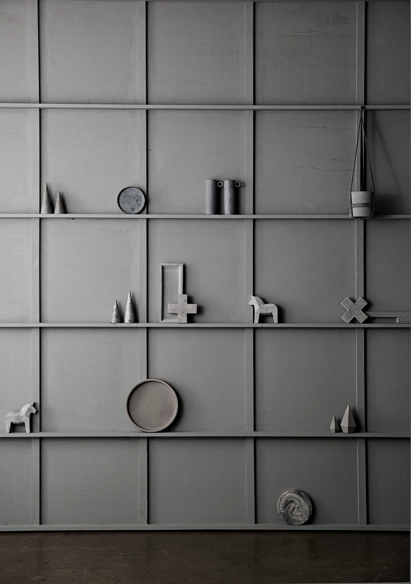 A natural gray shelf with a variety of objects on it, including a ZAKKIA Concrete Cross Trivet and ZAKKIA items.