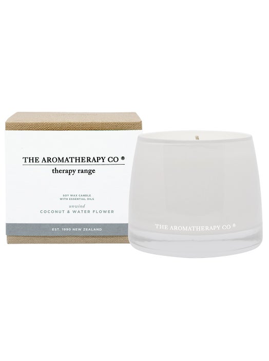 Therapy Unwind Coconut & Water Flower candle in white glass beside its white box